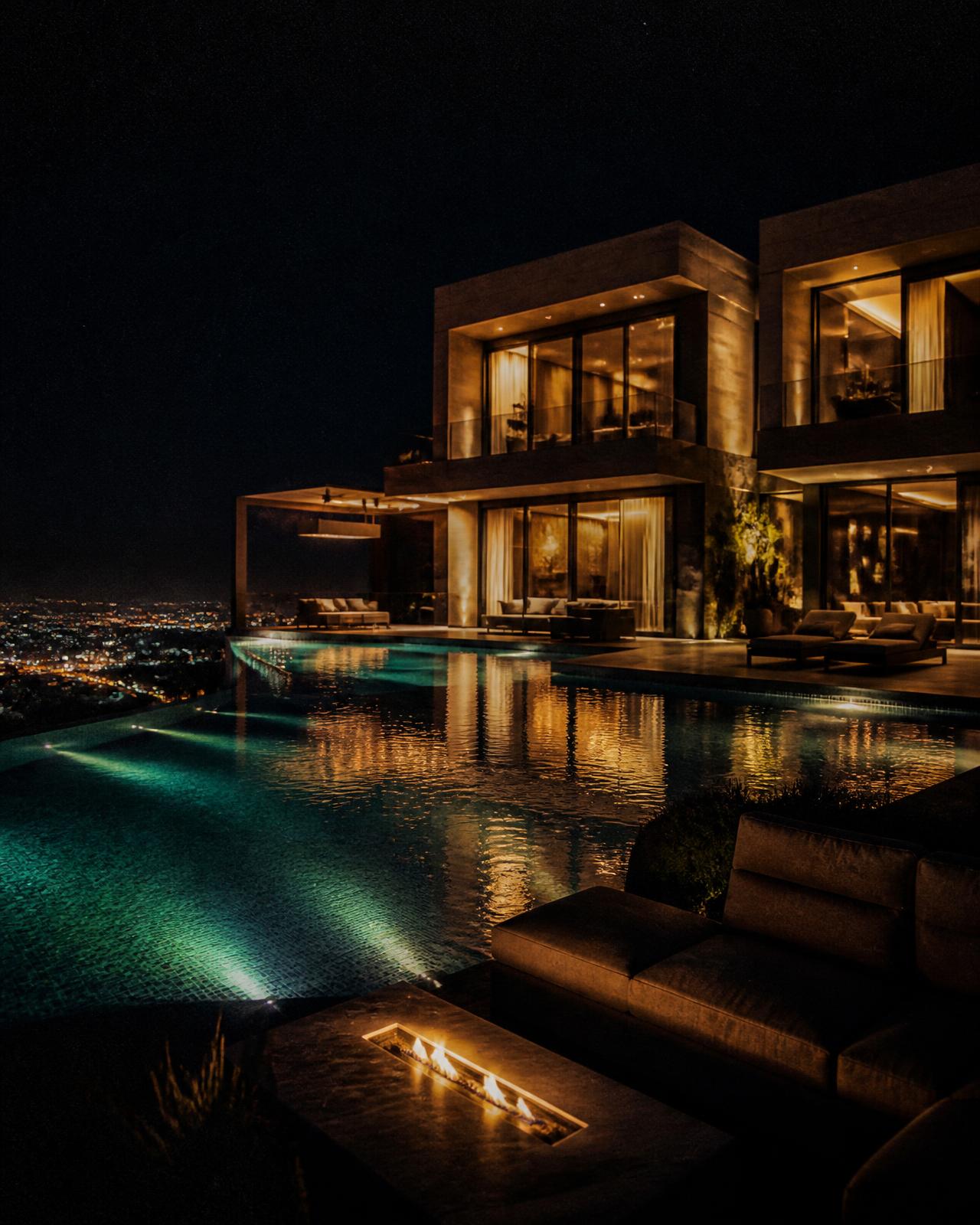 Modern luxury villa lit at night above an infinity pool